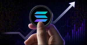A hand holding a physical Solana (SOL) coin in front of a glowing upward-trending arrow and a purple digital binary code price chart background.