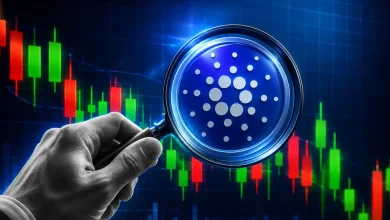 A hand holding a magnifying glass over a blue Cardano ADA token against a dark candlestick chart background.