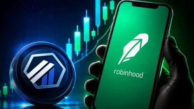 A hand holding a smartphone showing the Robinhood app next to an Arbitrum token.