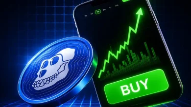 A blue ApeCoin coin sitting next to a smartphone displaying a steep green upward chart.