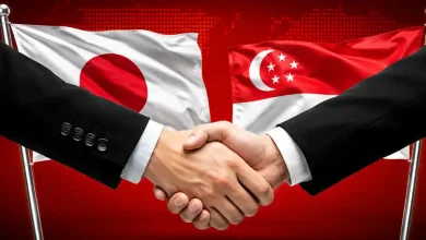 Handshake in front of Japan and Singapore flags.