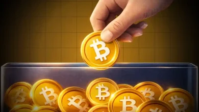 Hand placing a golden Bitcoin token into a transparent glass container filled with coins.