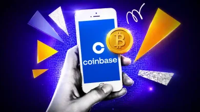 Hand holding a phone displaying the Coinbase logo and a Bitcoin coin.