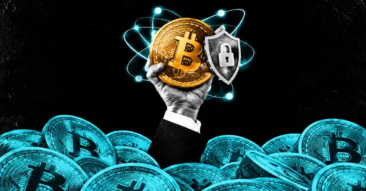 Hand holding a Bitcoin coin with a padlock shield surrounded by atomic quantum orbits